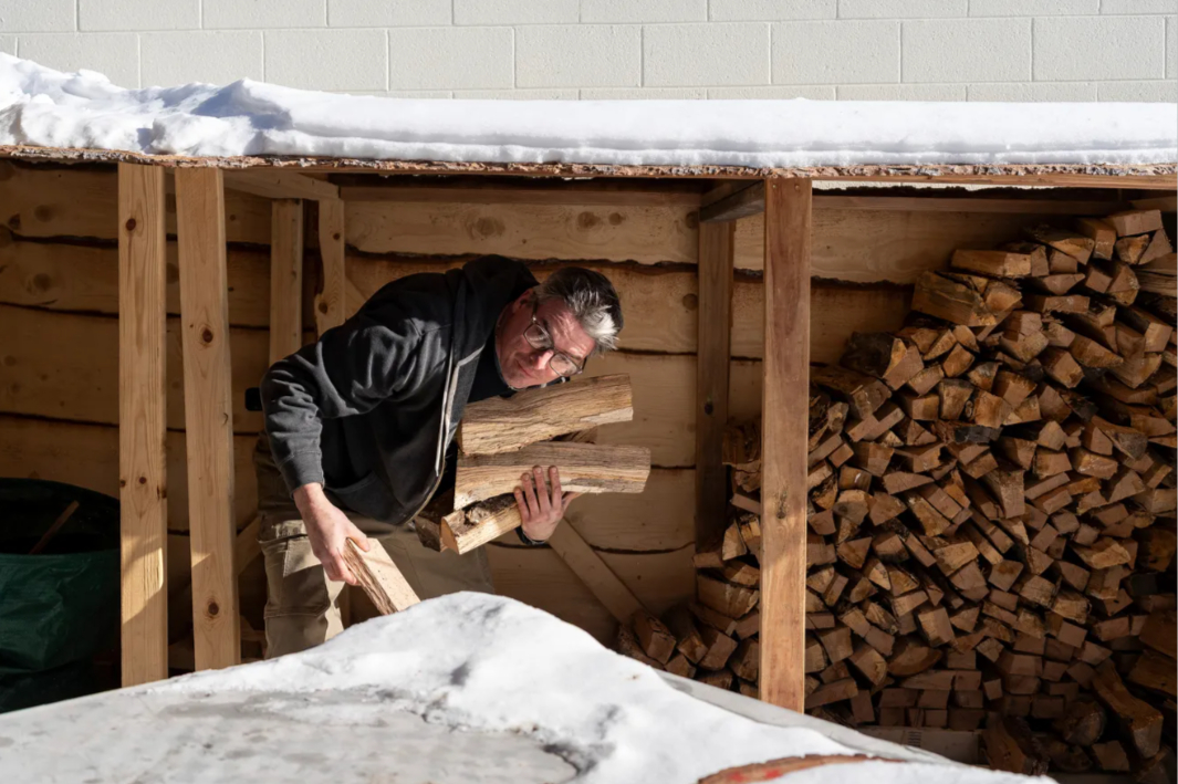 Randall Kuna stacking split cherry and apple wood at the woodshed